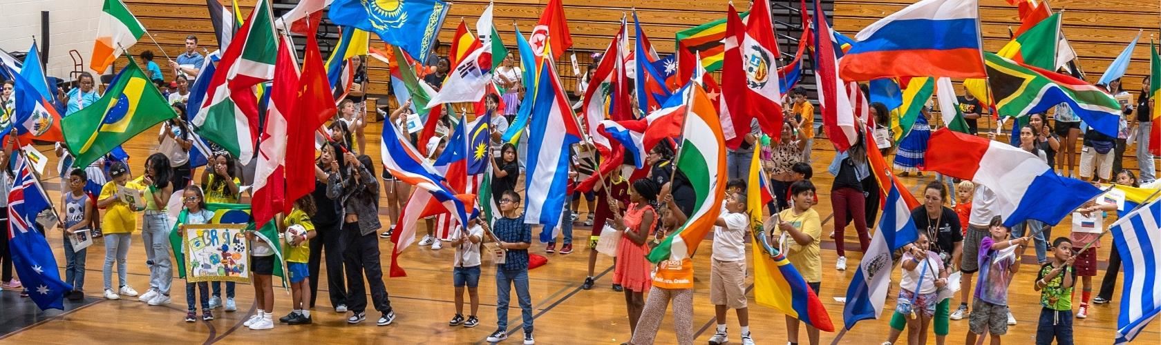 students in gym holding country signs and world flags